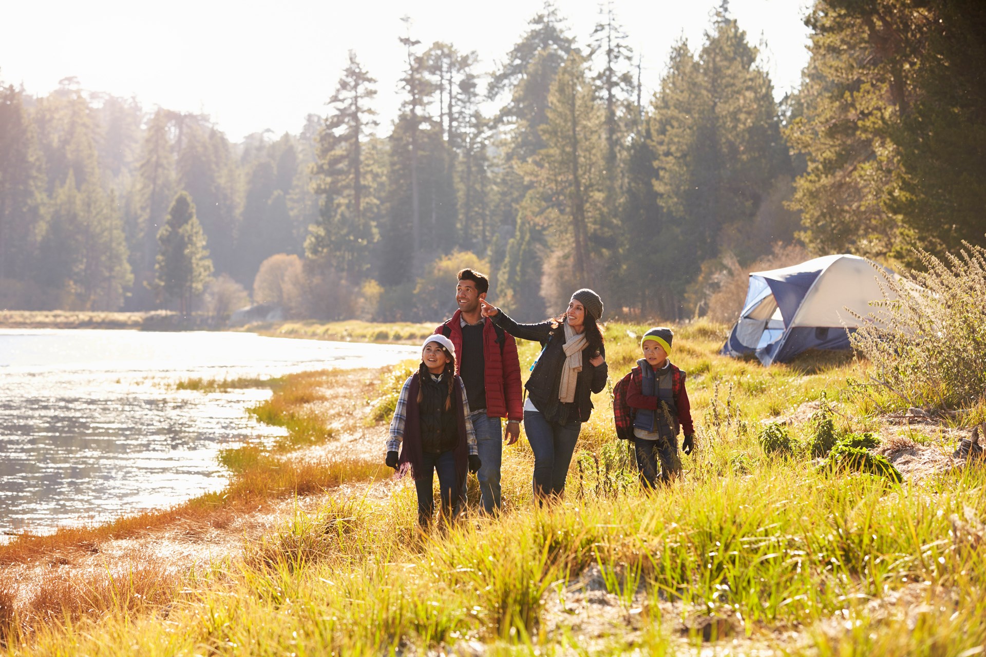 Family hiking next to a lake. via KOA website